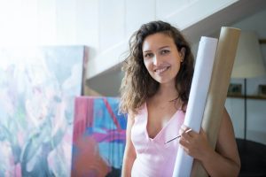 woman in pink sleeveless dress holding white and brown rolled paper