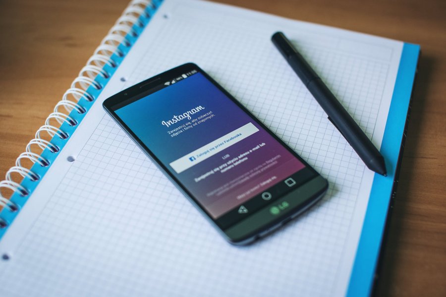 instagram on a phone with graphic design pencil and a notebook