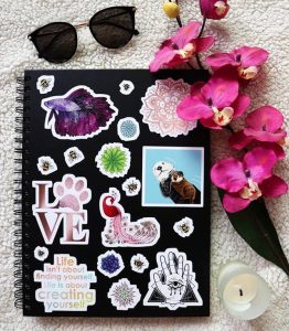 redbubble stickers on a black sketchbook or ntoebook